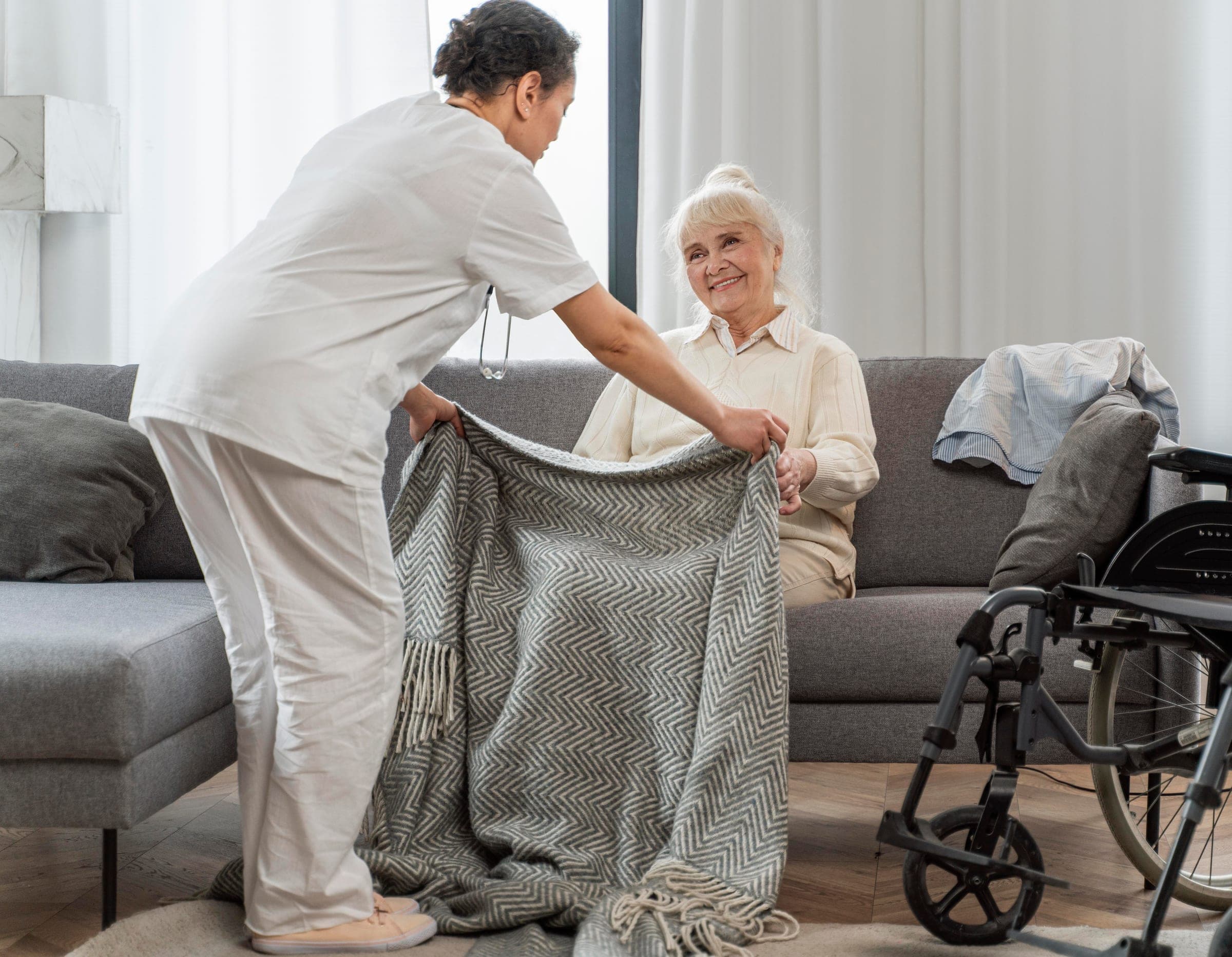 A caregiver arranging a soft throw for an elderly client at home